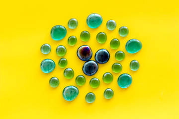 Shiny glass stones for decoration, creativity and craft on yellow background top view