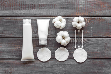 pattern of cosmetic cotton swabs, pads and cream on wooden background top view