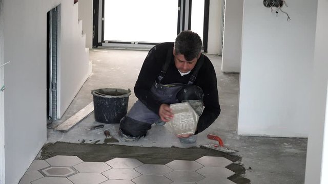 Laying hexagon tiles on floor. Pressing down and regulating