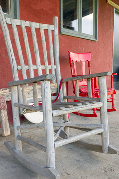 two wooden rocking chairs red and gray on a farm terrace in a village