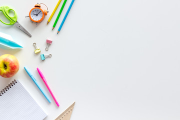 Back to school with stationary, notebook and alarm clock on white student desk background top view mock-up