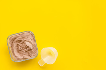 Sport diet with protein powder on yellow background top view copyspace