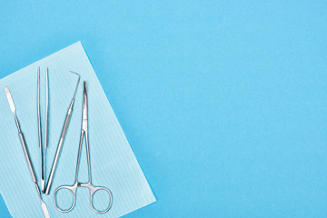 top view of metallic set with dental tools on apron isolated on blue