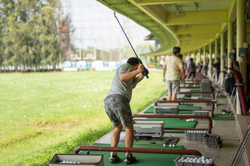 Man practicing his golf swing at golf driving range.