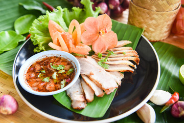 Roasted pork sliced baked pork grilled with spicy sauce and sticky rice herbs spices ingredients fresh vegetable served on plate in the wooden table , Thai Asian food