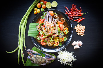Seafood salad spicy with fresh shrimp crab cockles served on black plate fresh vegetables herbs and spices ingredients with chilli tomato peanut garlic green papaya shredded Som tum Thai menu Asian