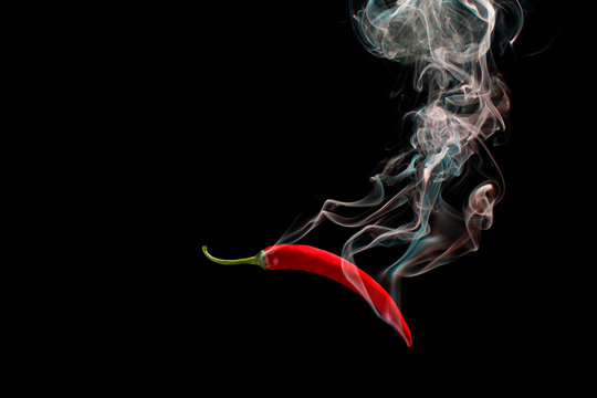 Red chili with smoke on a black background, the concept of spicy