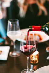 Red wine being poured on dinner table 
