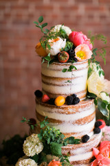 Obraz na płótnie Canvas Modern Naked Wedding Cake with Colorful Summer flowers, pink and orange flowers on wedding cake table