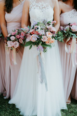 bride and bridesmaids holding wedding bouquets, pink bridesmaids dresses, detail shot, copy space