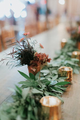  garland of greenery on wooden table, flower arrangements, tea candle lights, wedding reception decor