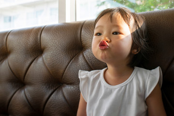 A little Girl Make fun kissing jokes on sofa,with copy space.
