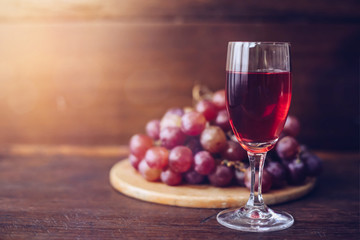 Close-up of a wine glasses  over grape on wood plate against window light  on wooden table, christian background with copy space 