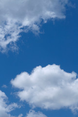 Background of blue sky with white fluffy clouds. Cropped shot, vertical, outdoors, nobody. Concept of nature and ecology.