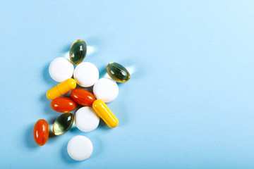 A lot of bright colored medicine pills on a blue background. Cropped shot, vertical, top view, close-up, free space. Medicine concept. Crisis of opioid painkillers and addiction concept.