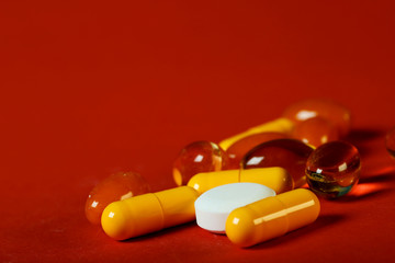 A lot of bright pills of drugs on a red background. Cropped shot, horizontal, side view. The...