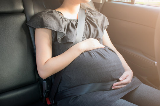 Pregnant woman wear safety seat belt in the car.