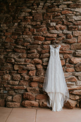 Modern Lacy Wedding Dress Hanging on Stone Wall, Copy Space, Classic Wedding Gown
