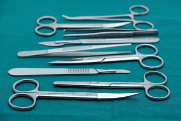 Basic surgical instrument scalpel forceps tweezers scissors on surgical green drape fabric