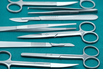 Basic surgical instrument scalpel forceps tweezers scissors on surgical green drape fabric