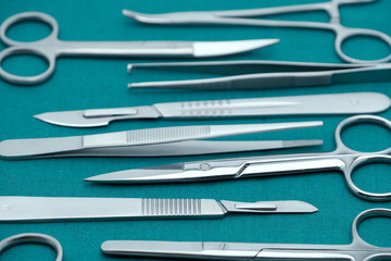 Basic surgical instrument scalpel forceps tweezers scissors on surgical green drape fabric