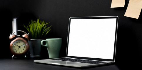 Dark luxury workplace with blank screen laptop computer
