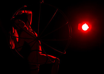 silhouette of sexy woman in red light on a dark background. leggy woman in a bodysuit with metal rings