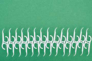 flat lay of white floss toothpicks isolated on green