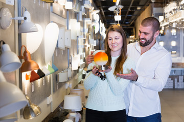 Smiling family  holding bedside lamp in furniture shop