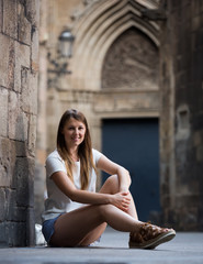 Fototapeta na wymiar Romantic girl sitting near stone wall