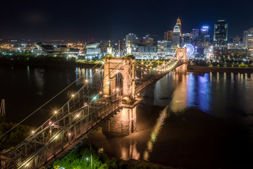 Obraz premium Aerial night view of the Roebling bridge in Cincinnati Ohio with a Ferris wheel in the background