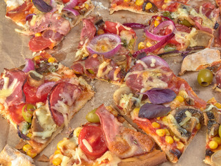 Pizza on thin dough.With slices of salami and ham ,olives and tomatoes.