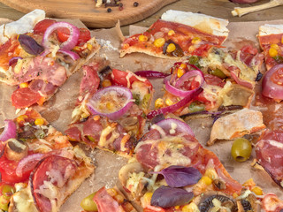 Pizza on thin dough.With slices of salami and ham ,olives and tomatoes.