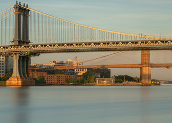 East river view with Manhattan and Brooklyn Bridges at sunrise with long exposure