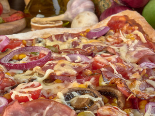 Pizza on thin dough.With slices of salami and ham ,olives and tomatoes. 