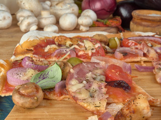 Pizza on thin dough.With slices of salami and ham ,olives and tomatoes. 