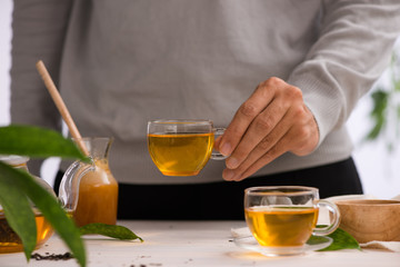 Male hands holding cup of tea glass on light background