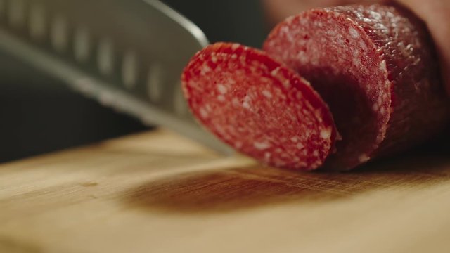 SLOW MOTION: Man Slicing A Piece Of Salami Suasage On Cutting Board