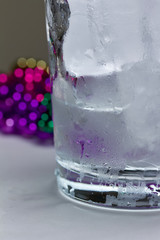 Abstract close up view of a beverage glass with ice and condensation on a white background