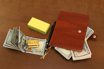 On the office desk are cash dollars, gold bars. Notepad for notes and pen.