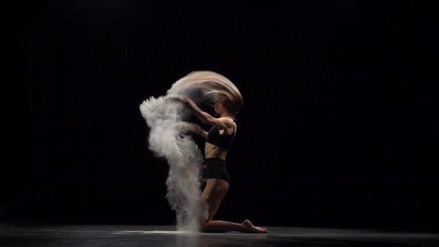 Slow motion of professional dancer throwing dust particles in air.