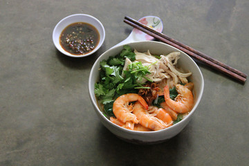 Shredded chicken, savoury broth, and prawn chili oil paired with Ipoh's signature kway teow noodle make up the delicious bowl of noodles in Ipoh, Malaysia.
