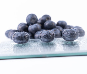 Delicious wet blueberries on a glass plate - Ripe blueberries - Blueberries on a white background