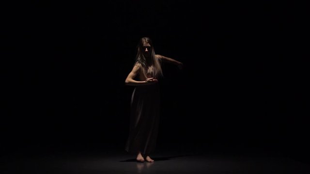 Woman performing contemp in twilight of studio. Slow motion