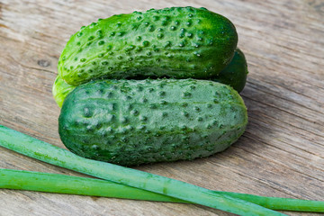 Fresh small green cucumbers on an old wooden table, summer vegetable harvest close-up