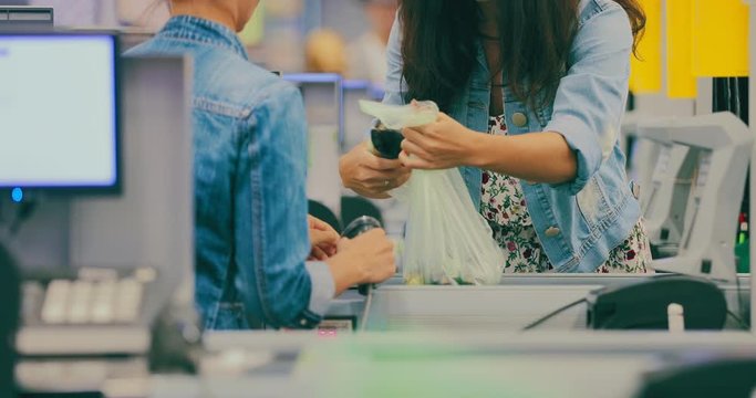 Girl puts vegetables at the checkout. Shopping at the supermarket.