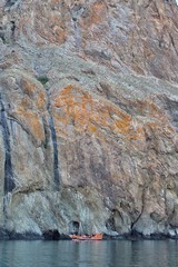 A small ship on the background of a large rock.