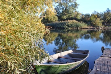Naklejka premium wooden boat at the pier, reed
