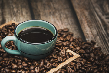 cup of coffee with beans on brown wooden table