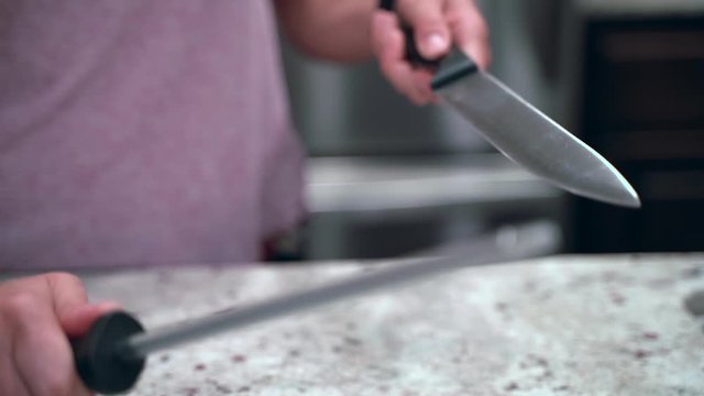 Close up of woman sharpening a knife over a countertop in slow motion